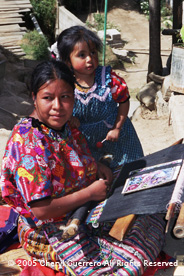 Julia Lopez follows a printed pattern as she weaves in the family compound with her youngest daughter nearby.  Julia, 19, had her first child at age 11.  Photo by Cheryl Guerrero 2005.