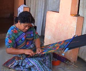 Esperanza Lopez clips dangling supplementary weft threads from a huipil or blouse panel woven on a back strap loom in the style of her community.  Photo by Beth Riley 2005.