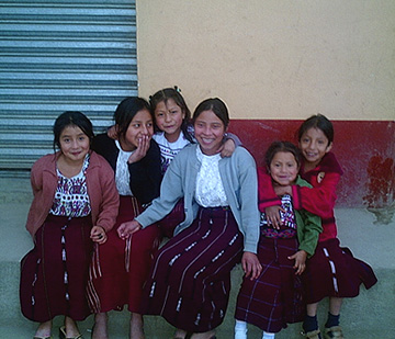 Schoolgirls in Nebaj giggle with embarrassment after begging to be photographed.  The Peace Accord of 1996 gave indigenous children the right to wear traje to school, though in large cities few do.  Photo by Kathleen Mossman Vitale 2005.