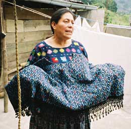 Doña Flor Xoc, president of Nu'Kem Association of Weavers in Tactic and Tamahú in Alta Verapaz, shows off a heavy cotton huipil she wove several years ago.  Photo by Margot Blum Schevill 2005.