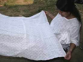 Picb'il weaver Concepción Poou Coy de Tharin wears her wedding huipil or blouse and shows off an uncut picb'il huipil from Alta Verapaz.