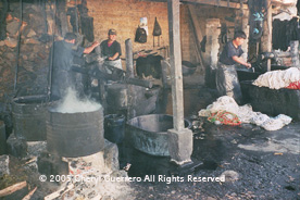 At a dye workshop in Salcajá, workers stoke the fires and submerge bundles of tied thread that will be used later in jaspe or ikat weaving.  Photo by Cheryl Guerrero 2005.