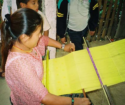 Matilde Chup Cucul weaves yellow tablemats on a back strap loom for an export organization.  Photo by Margot Blum Schevill 2005.