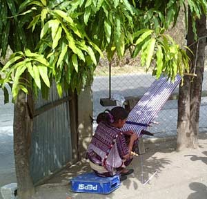 About 25 kilometers west of the city of Huehuetenango, near the community of San Rafael Petzal, Elena Domingo Mejía finds a shady spot near the Pan American Highway to weave.  Photo by Paul G. Vitale 2005.